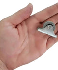 Mini caster wheel with rubber tire in metal housing held in hand (front view)