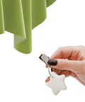 Hand holding a star-shaped marble tablecloth weight with clip, near green tablecloth. 10 Pack Marble Tablecloth Weights With Clips.