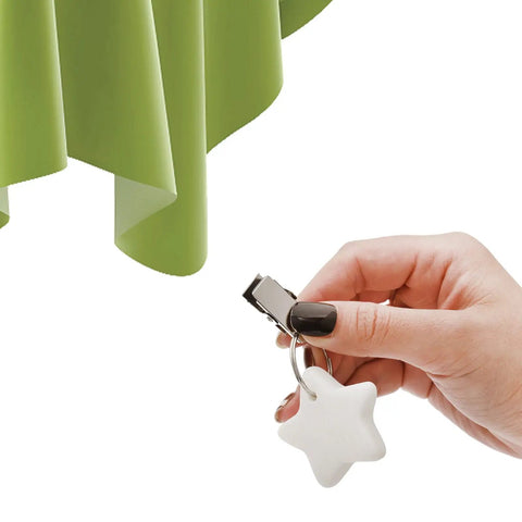 Hand holding a star-shaped marble tablecloth weight with clip, near green tablecloth. 10 Pack Marble Tablecloth Weights With Clips.