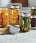 Real Deal Wide Mouth Glass Mason Jars With Lids And Bands For Canning And Pickling Quart 32 Oz Pack Of 2 filled with preserves and veggies.