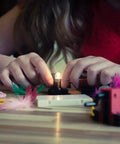 Child assembling Totally Hands On Electric Circuit Kit For Kids Diy STEM Learning Set with lit bulb on wooden table.
