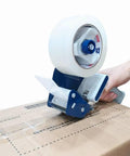 Pro Grade Heavy Duty Packing Tape Set With Tape Gun sealing a cardboard box, showing tape roll and blue dispenser in use.