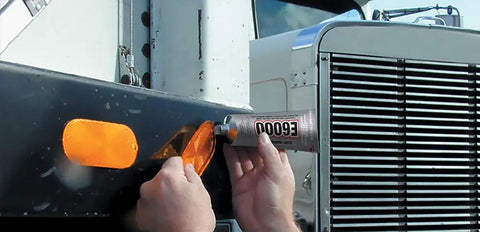 Applying Hi Visc 3.7-Ounce Adhesive Go-To Bond on vehicle light for tough projects; ensures strong, flexible bond on metal surface.