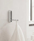 Sleek Black Folding Wall Hooks Four Pack With Swivel Hinge Design Perfect For Tight Spaces And Narrow Hallways No Hassle Kickback Mount holding a towel.