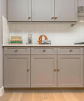 Round Knobs 1 Inch Solid Zinc Alloy Antique Brass Cabinet Handles, 4 Pack, on gray kitchen cabinets.