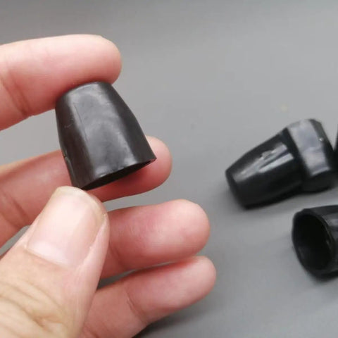 Close-up of hand holding a 15mm black plastic dust cover, part of 8 Pack Fifteen Millimeter Bike Hub Axle Dust Covers Replacement End Caps.