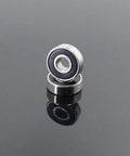 Pro Grade 608 2RS Hybrid Ceramic Bearings With Abec 7 Precision An 8 Pack Sized At 8X22X7MM For Skateboards And Roller Skates view of two ceramic bearings on a reflective surface.