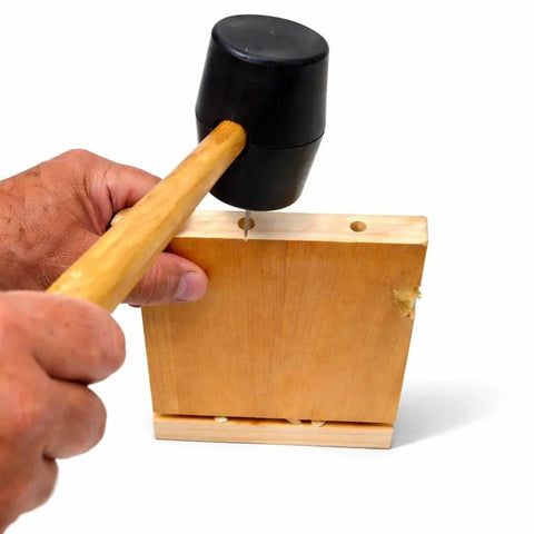 Person hammering a Pro Grade Fluted Birch Wood Dowel Pins 3/8 x 1-1/2 Inch into wooden board for joinery project