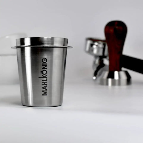 Barista Level Electric Coffee Grinder With Stepless Control And 54Mm Steel Flat Burrs Delivers Hella Consistent Grounds For Quick Home Brewing Features A Sleek Chrome Body And Easy Clean Design To Keep Your Daily Cup Straight Up Perfect, stainless steel cup with Mahlkönig logo.