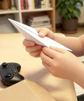 Hands holding a paper plane near a remote control, Electric RC Paper Airplane Kit With Gyro Stabilizer And Dual Propellers For DIY Flight