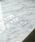 Upgraded Heavy Duty Nano Acrylic Gel Small Clear Adhesive Hooks 36 Pack Damage Free Mini Wall Hangers arranged on marble surface.