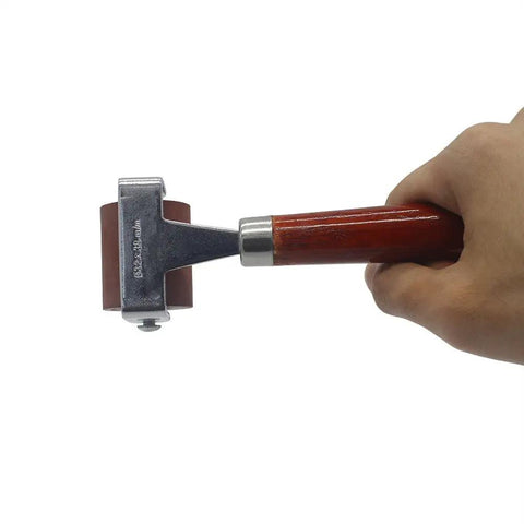 Hand holding Soft Rubber Brayer Roller with Wooden Handle for Printmaking, 32x38 mm roller, heavy stainless steel frame, side view
