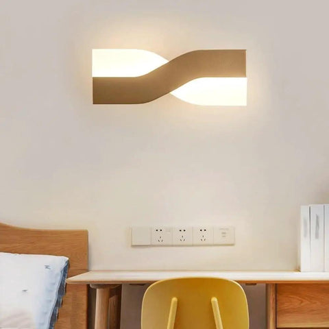 UPRENXIAO Modern Minimalist Nordic Led Wall Sconce Wavy Twisted Design Baked mounted above a desk in a cozy bedroom setting.