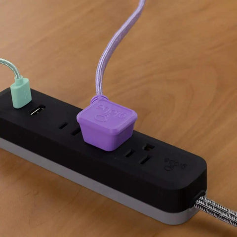 Close-up of Dope Designer Series Rose Power Strip with 3 outlets, dual USB ports on a desk with purple and green plugs connected.