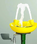 Yellow Wall Mounted Emergency Eyewash Station With Dual Spray Heads And Hands Free Activation 15 Minute Flush Traditional Series Safety Eyewash For Industrial Lab And Workplace Environments with water spraying.