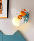 Bee Shaped Kids Wall Light With Glass Shade cute sconce on wall in children's bedroom, modern decor for reading and playtime.
