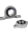 Premium Zinc Alloy Pillow Block Bearing KP000 Series Heavy Duty Mounted Bearings Keep Your Machine Running Smooth with Anti Rust and Corrosion Proof Sealed Units Designed for Continuous Load Cycles Get a Rock Solid Performance Many Sizes Ready Now. silver pillow block bearing, front and top views