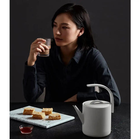 Sleek 850Ml Electric Brewing Kettle With Quick Boil Tech and Smart Auto Pour placed near snacks on a dark table.