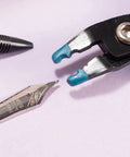 Close-up of a plier gripping a fountain pen nib with a Nib Removal Tool Kit With Plier And Rubber Sheet For Fountain Pen Nib Slit Widening And Protection.