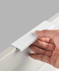 Hand holding one Six Pack Finger Edge Drawer Pull Handles In Bright White For Cabinets And Kitchen Drawers Hidden Mount Aluminum Hardware.
