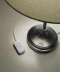 Credenza Plug-In Dimmer for Incandescent and Halogen Lamps With Locator Light next to a table lamp base, white finish