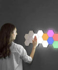 Person activating 12 Pack LED Hexagon RGB Lights Modular Touch Sensitive Wall Light Kit With Magnetic Reusable Tiles Lit Color Changing Glow Tap To Power Expandable Lighting System