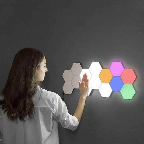 Person activating 12 Pack LED Hexagon RGB Lights Modular Touch Sensitive Wall Light Kit With Magnetic Reusable Tiles Lit Color Changing Glow Tap To Power Expandable Lighting System