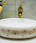 Slick Ceramic Oval Vessel Sink For Modern Bathroom Counters Smooth Glazed Finish with floral designs and gold faucet.