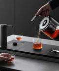 Premium 800Ml Electric Tea Maker Featuring Auto Water Pump And Secure Magnetic Lid pouring tea into a glass.