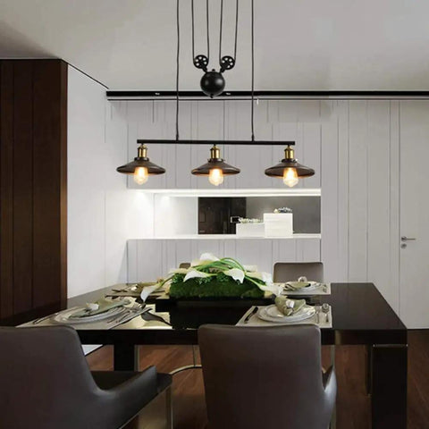 Fresh Vintage Industrial Billiard Chandelier Features Easily Adjustable Pulley Lift System In Classic Black Metal Three Light Ceiling Hanging Lamp above a dining table.