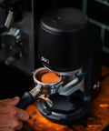 Electric Auto Leveling Espresso Tamper For 57.3 Mm Portafilters with portafilter and tamper, showcasing use in home kitchen.