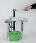 Beefy Three Arm Puller 375mm Heavy Duty Gear Puller in action removing a green flywheel, with a hand turning the wrench.