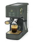 Rock Solid Compact Espresso Machine In Fresh Thyme Green brews espresso with rich crema in a glass on a gold drip tray.