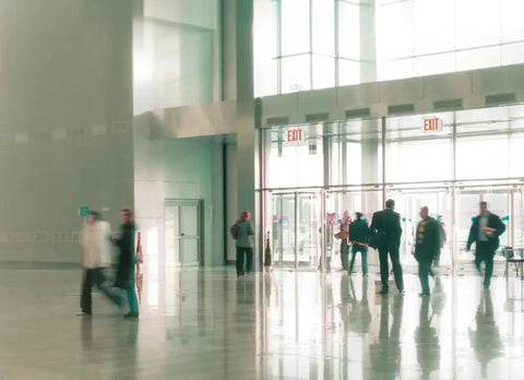 Lobby with exit signs, illustrating Single-Sided LED Exit Sign With Thermoplastic Housing And Switchable Red Or Green.