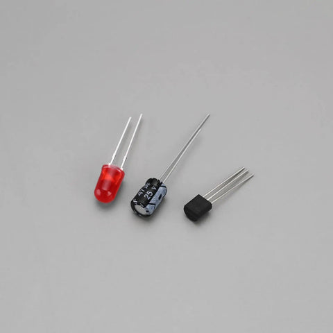 Components for Two Piece Heart Shaped LED Soldering Practice Kit With Flashing Lights, including red LED and capacitors