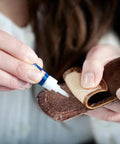 Loctite Super Glue Liquid, clear adhesive in 0.07 fl oz tube, close-up applying to brown leather strap