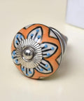 Close-up of a 50 Pack Flower Ceramic Mustard Drawer Knob for Kitchen Cabinets, orange floral design with silver hardware.