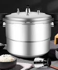 Stainless steel pressure cooker with jigger relief valve set on lid; detached valve component beside it.