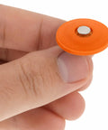 Resilient orange waterproof washer held between fingers for No Fuss Plastic Cap Nails Paired With Heavy Duty Electro Galvanized Ring Shank Fasteners And Resilient Orange Waterproof Washers For Fast Tar Paper And Roof Deck Work.