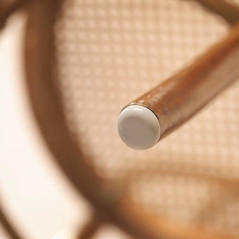 Close-up of a chair leg with a white Peel And Stick Furniture Sliders Value Pack For Carpet Floors for smooth movement.