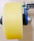 Close-up of Badass Heavy Duty Swivel Caster Wheel with yellow nylon roller, blue bracket, and measuring tool.