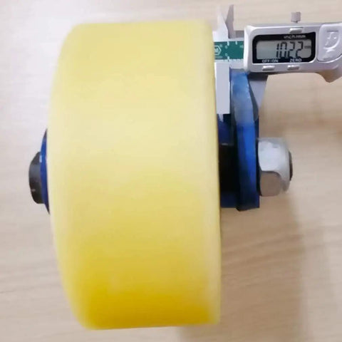 Close-up of Badass Heavy Duty Swivel Caster Wheel with yellow nylon roller, blue bracket, and measuring tool.