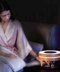 Woman using Bonsai Modern LED Bedside Smart Table Lamp With Built In Bluetooth Speaker And Qi Wireless Charger in dim room