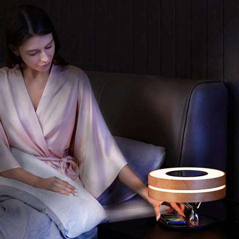 Woman using Bonsai Modern LED Bedside Smart Table Lamp With Built In Bluetooth Speaker And Qi Wireless Charger in dim room