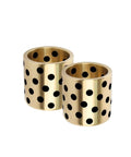 Flanged Steel And Copper Linear Bearing Sleeve Designed For CNC And 3D Printers Runs Slick As Butter With An Oil Free Graphite Core That Slides Perfectly And Cuts Down On Maintenance Hassles Today, two bronze sleeves with black dots.