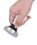 Hand holding a 58 Millimeter Size Coffee Tamper Top Tier Stainless Espresso Press with smooth grip for brewing.