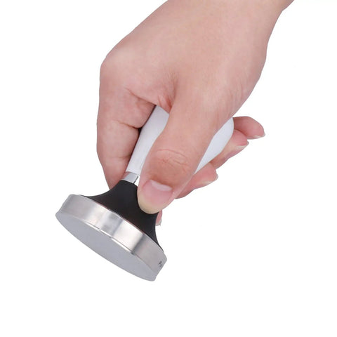 Hand holding a 58 Millimeter Size Coffee Tamper Top Tier Stainless Espresso Press with smooth grip for brewing.