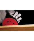 Hand using Hook And Lock ROS Sanding Discs For Wood Metal And Plastics 5 Inch 60 Grit Coarse Ceramic on wood surface