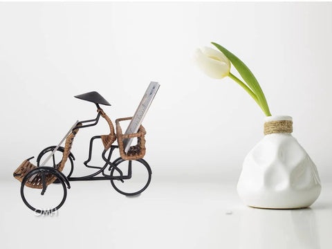 Killer Vintage Asian Rickshaw Driver Card Holder With Sleek Metal Body And Super Cool Rattan Detailing Perfect For Your Desk Or Shelves Bringing Fresh Home Office Energy To Your Space At Seven By Four Inches Wide on a minimalist background.