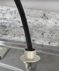 Heavy Duty Universal Faucet Hose Guide In Brushed Nickel with sprayer line coming out, mounted on kitchen sink deck.